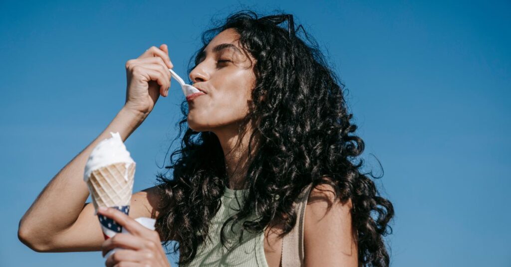 A woman eating an ice cream cone with a blue background