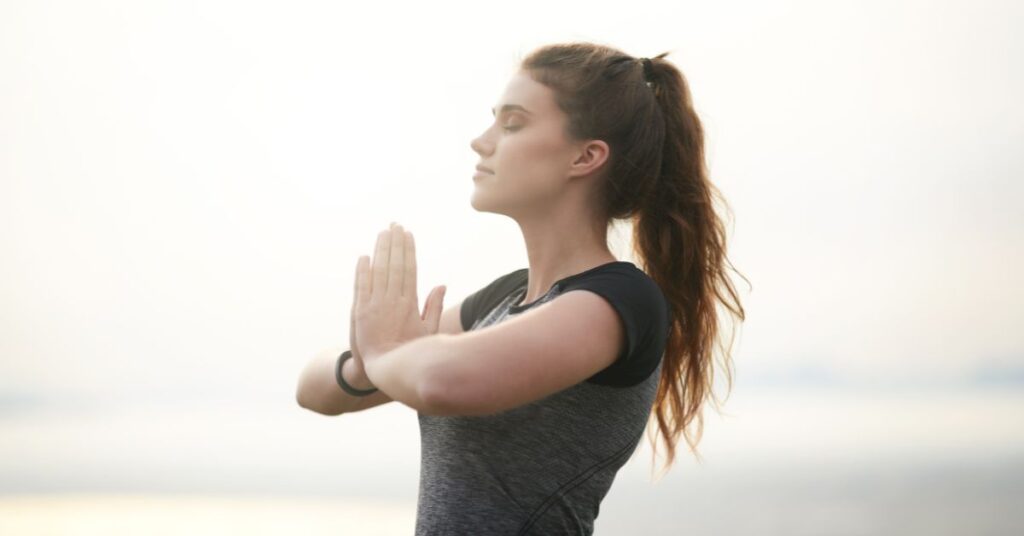 A woman with her hands at her heart and eyes closed