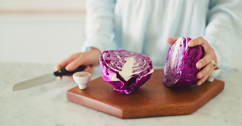A woman cutting a cabbage on a cutting board