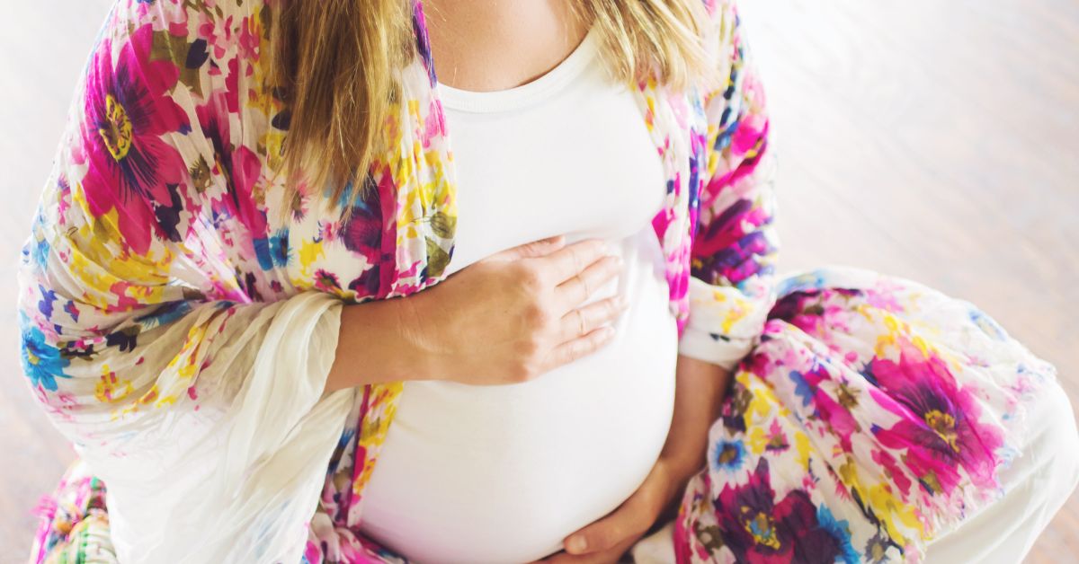 A close up of a pregnant woman holding her belly