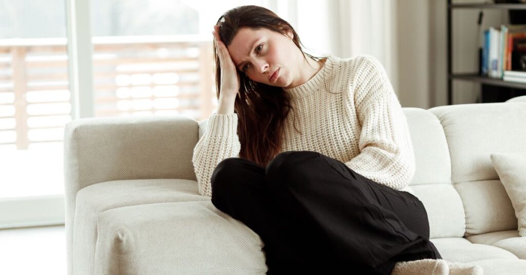A woman sitting on a couch with her head in her hands