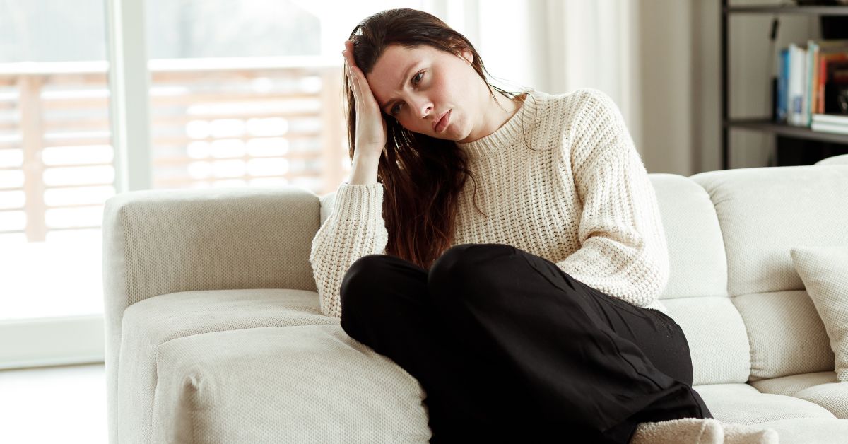 A woman sitting on a couch with her head in her hands