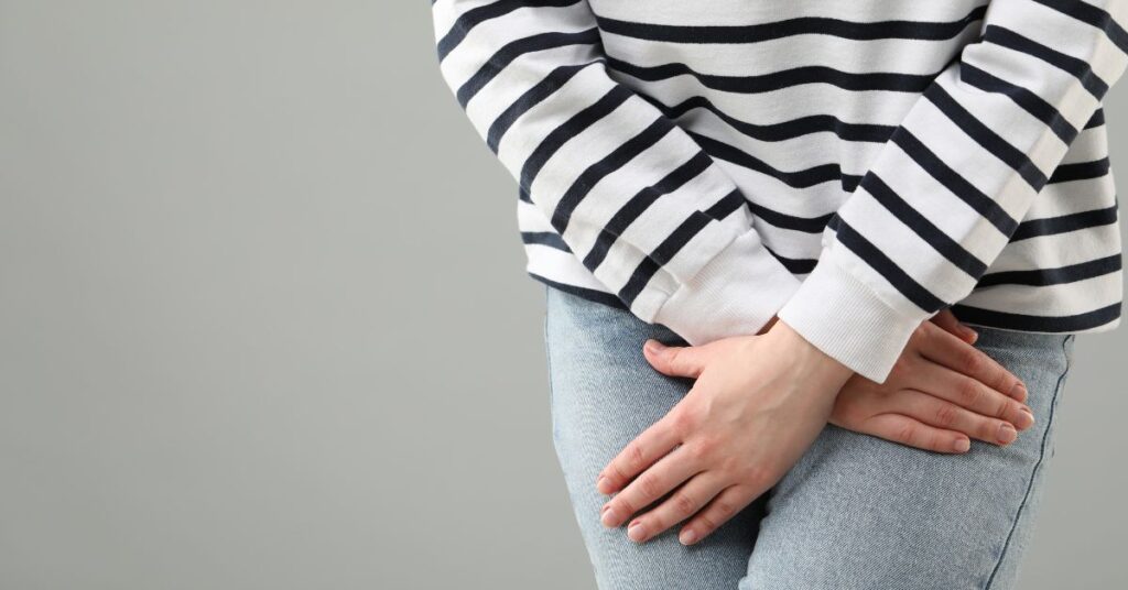 Woman crossing her legs with her hands over her bladder