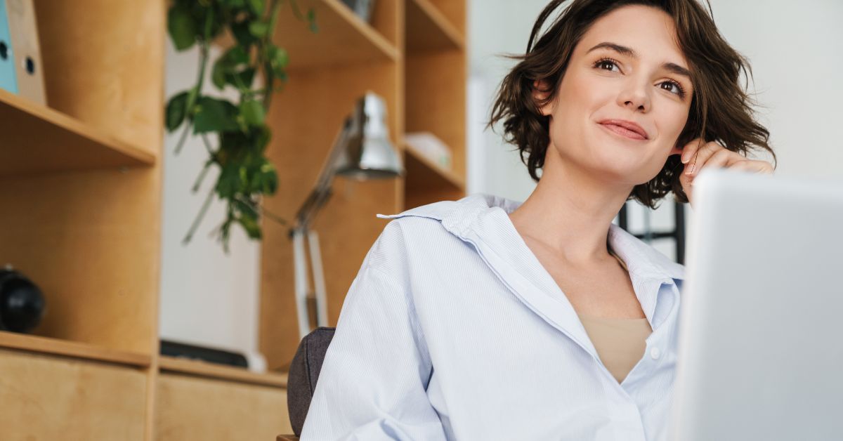 A woman sitting at her computer looking in the distance