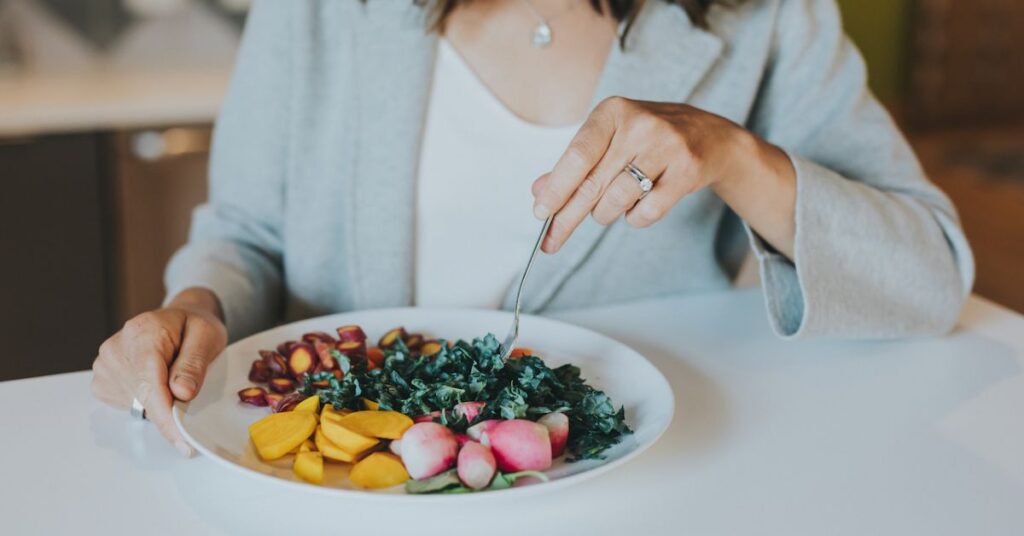 A woman eating a plate of vegetables
