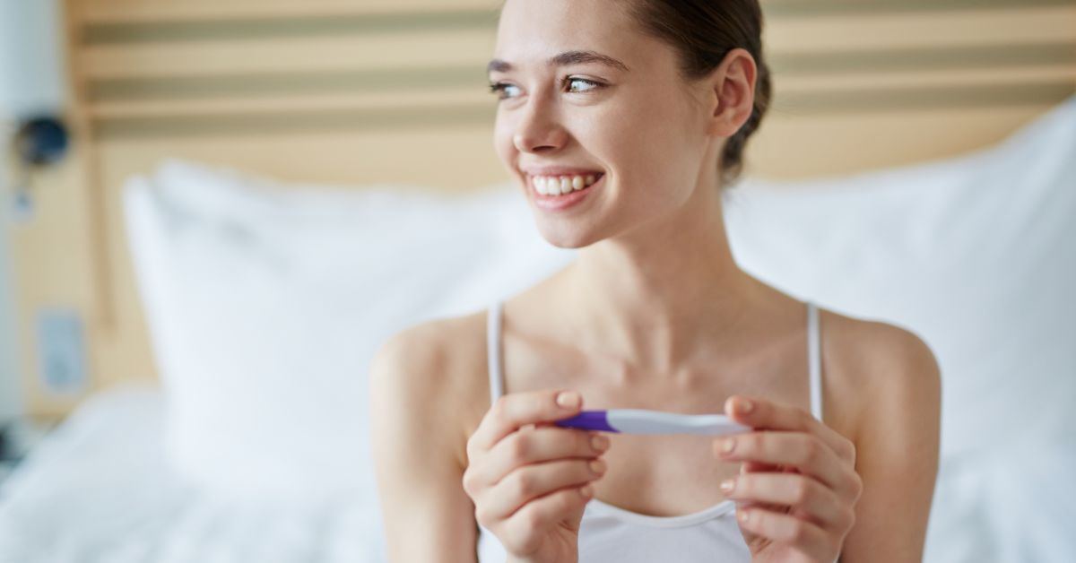 A woman holding a pregnancy test and smiling