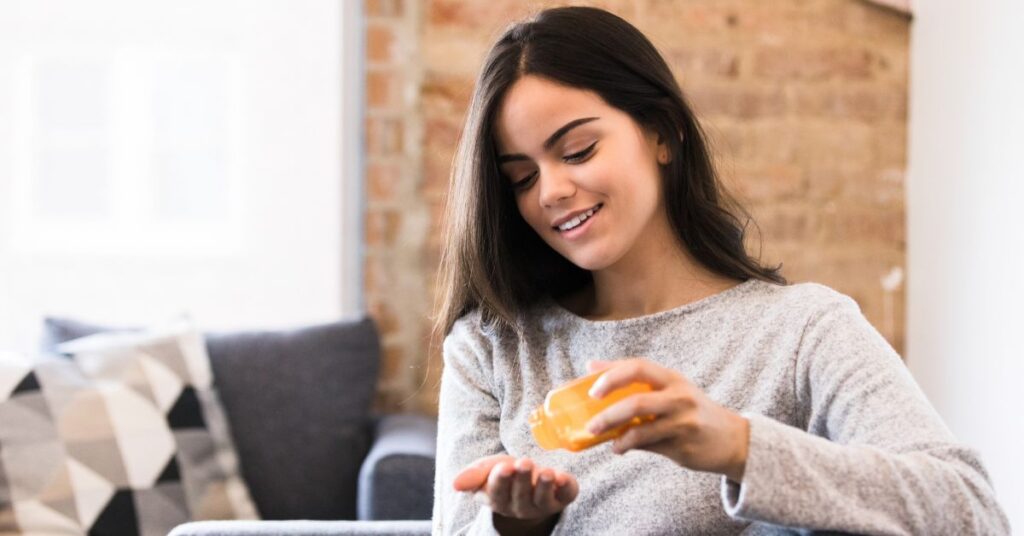 A young woman sitting on a couch taking her medication