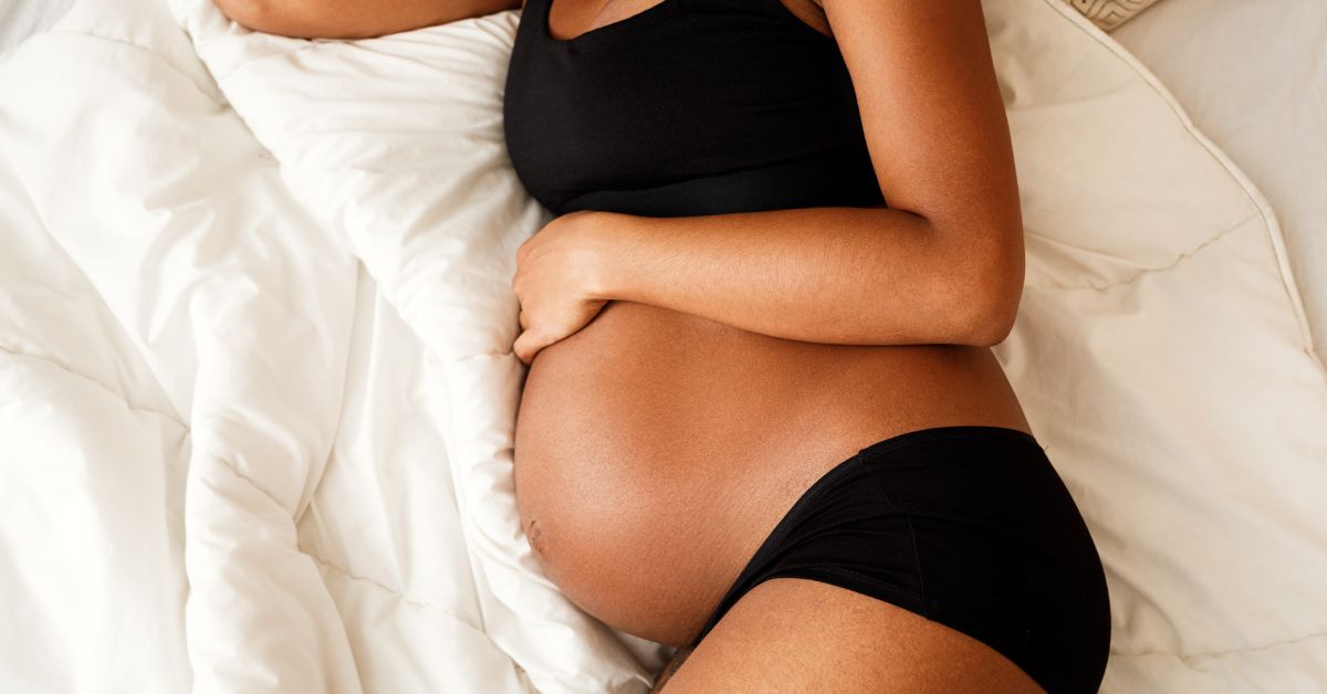 A flat lay of a pregnant woman laying on a bed