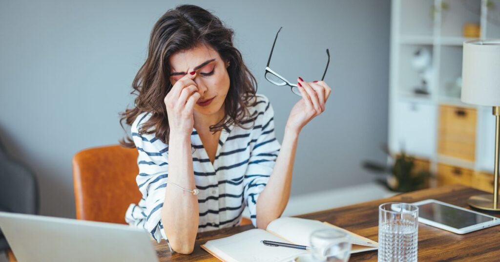 A woman stressed out at her computer rubbing her temple