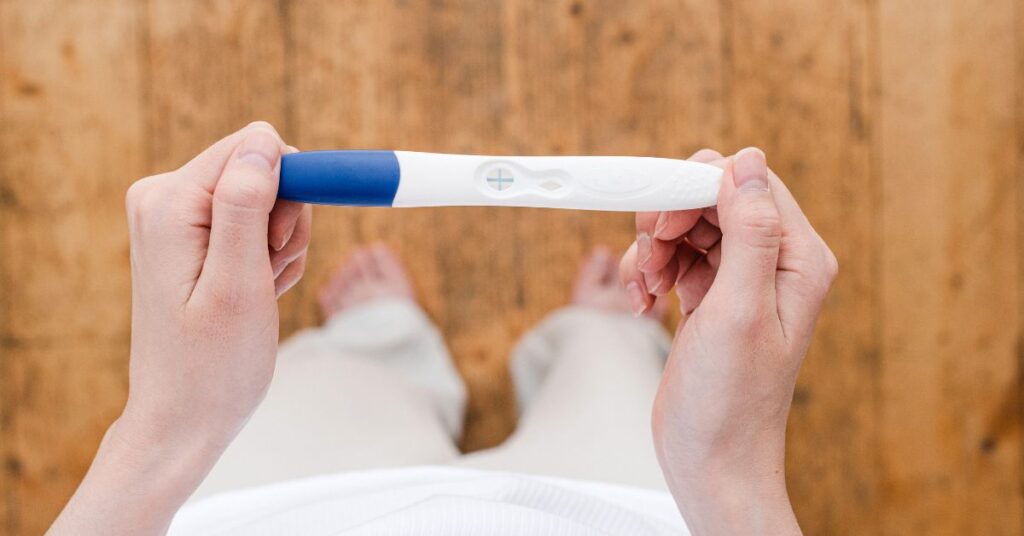 Flat lay of a woman holding a positive pregnancy test